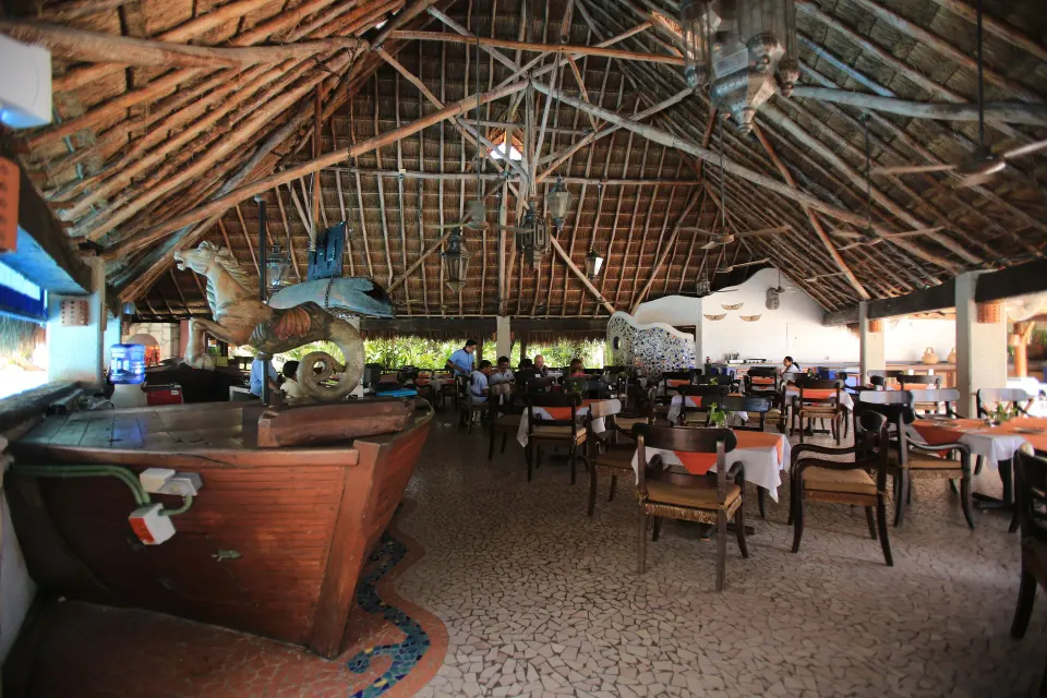 Interior view of the palapa restaurant showing tables and the thatched ceiling at Casa del Mar Cozumel Hotel & Dive Resort