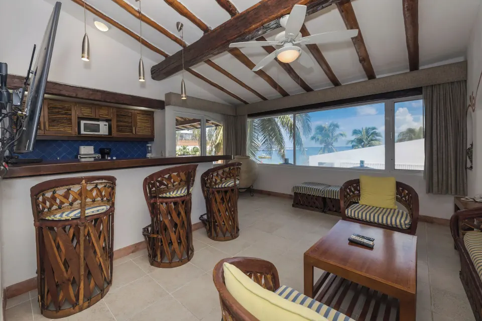 Indoor bar area with wooden stools and ocean view window at Casa del Mar Cozumel Hotel & Dive Resort