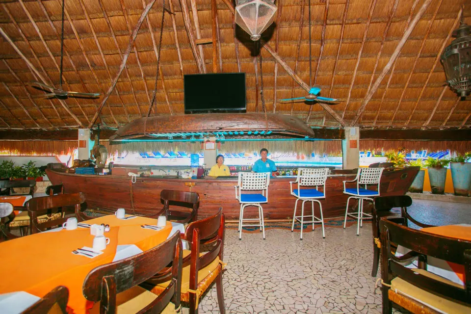 Resort bar with stools and TV under palapa at Casa del Mar Cozumel Hotel & Dive Resort