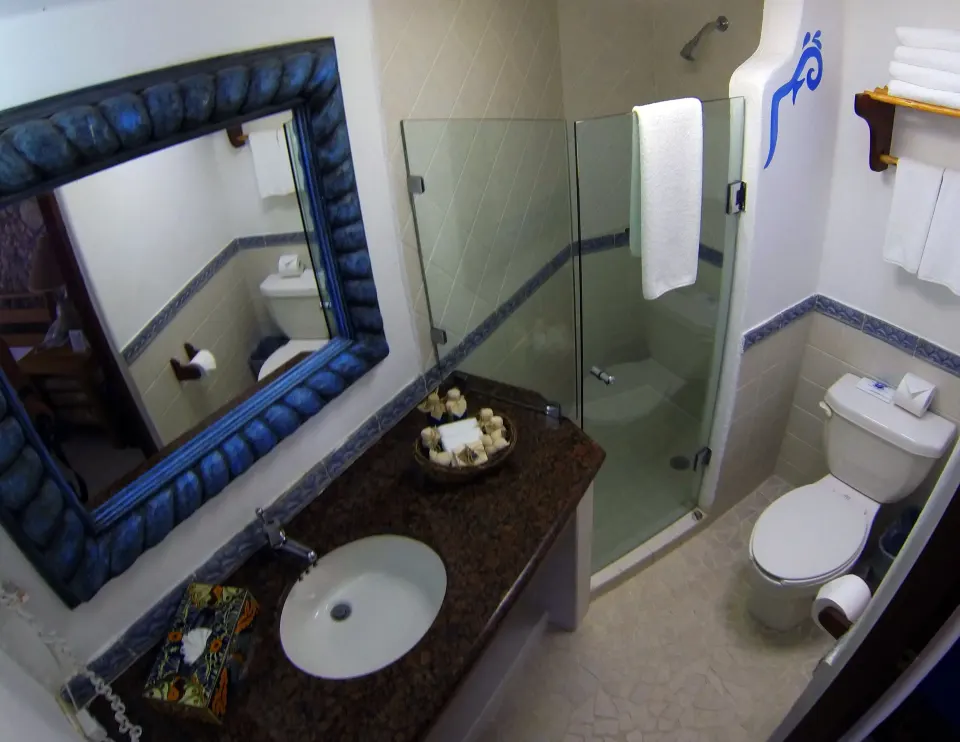 Bathroom with sink, mirror and corner glass shower at Casa del Mar Cozumel Hotel & Dive Resort