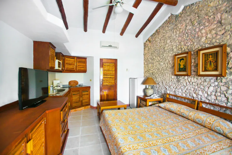 Wide view of a deluxe cabin with bed, kitchenette and vaulted ceiling at Casa del Mar Cozumel Hotel & Dive Resort