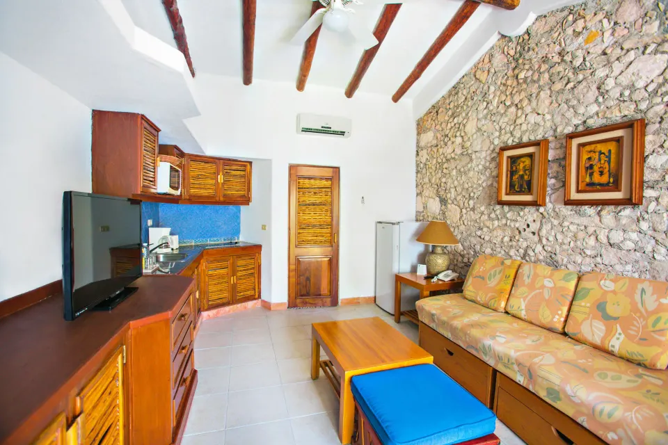 Deluxe cabin living area with kitchenette and stone wall at Casa del Mar Cozumel Hotel & Dive Resort