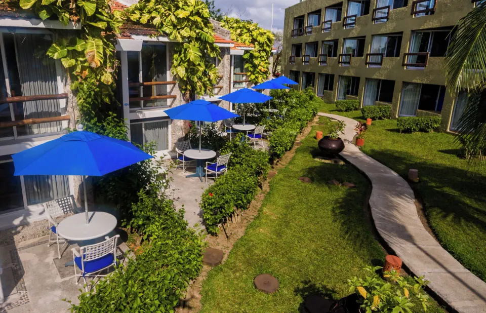 Ground-level garden courtyard with blue patio umbrellas at Casa del Mar Cozumel Hotel & Dive Resort