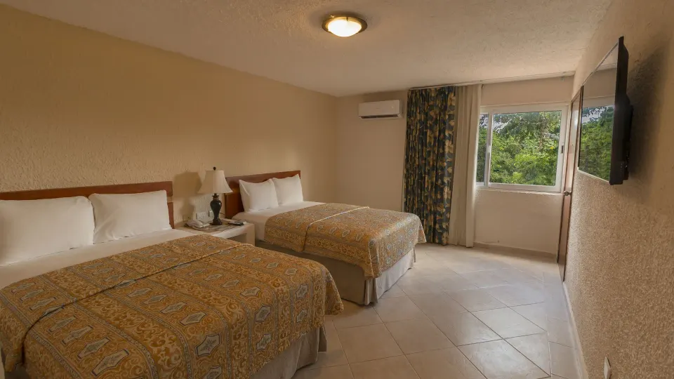 Family room with two double beds and a wall-mounted TV at Casa del Mar Cozumel Hotel & Dive Resort
