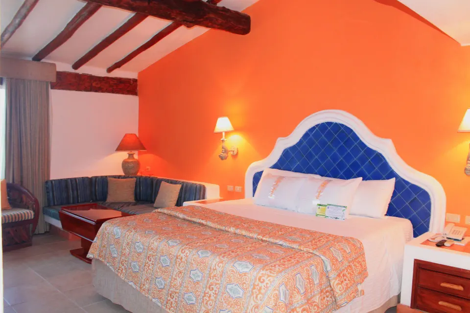 King bed with blue headboard and orange accent wall at Casa del Mar Cozumel Hotel & Dive Resort