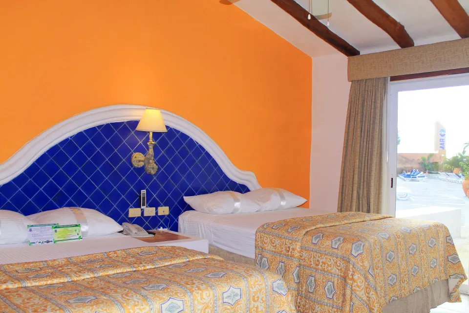 Two beds with ocean view visible through sliding door at Casa del Mar Cozumel Hotel & Dive Resort