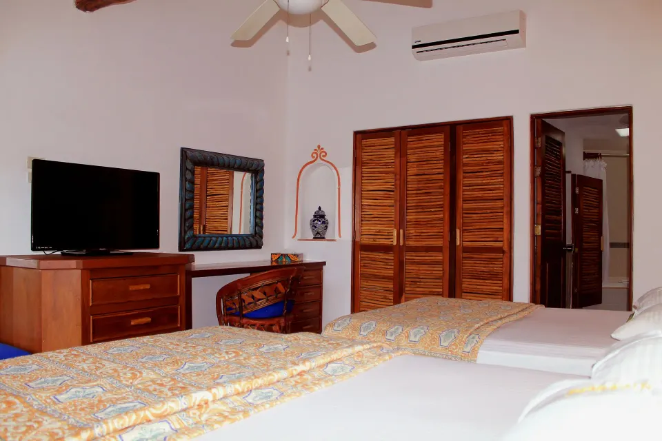Two double beds and wooden closet inside a guest room at Casa del Mar Cozumel Hotel & Dive Resort