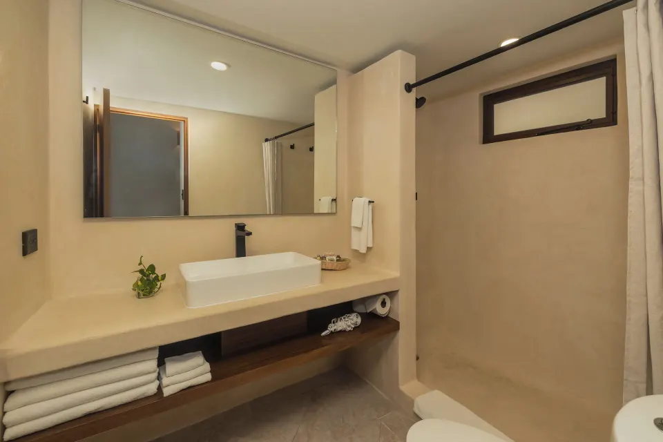 Bathroom countertop, mirror and shower area in a Superior Plus room at Casa del Mar Cozumel Hotel & Dive Resort