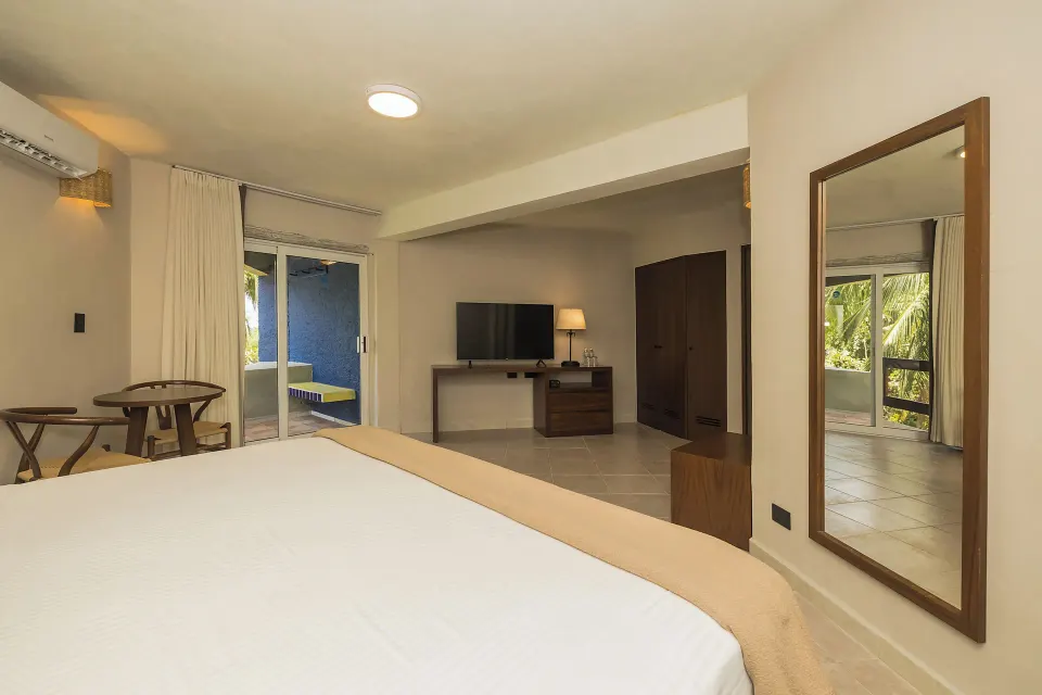 Bed foreground with TV and balcony visible in a Superior Plus room at Casa del Mar Cozumel Hotel & Dive Resort