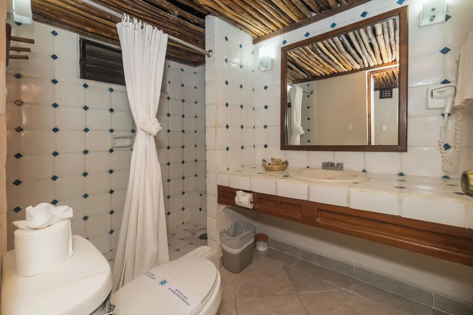 Bathroom with tiled shower, long vanity and mirror in a guest room at Casa del Mar Cozumel Hotel & Dive Resort