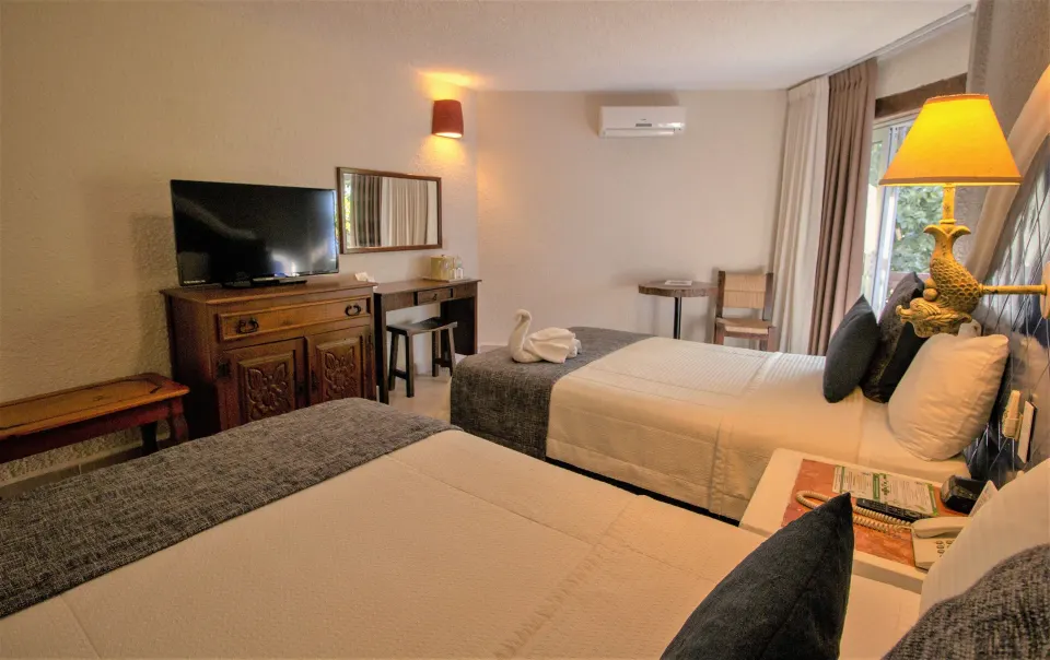 Warmly lit Superior Room with two beds and TV at Casa del Mar Cozumel Hotel & Dive Resort
