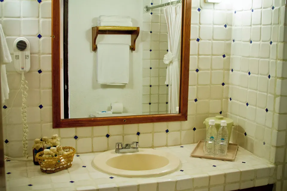 Vanity sink with mirror and bottled water in a guest bathroom at Casa del Mar Cozumel Hotel & Dive Resort