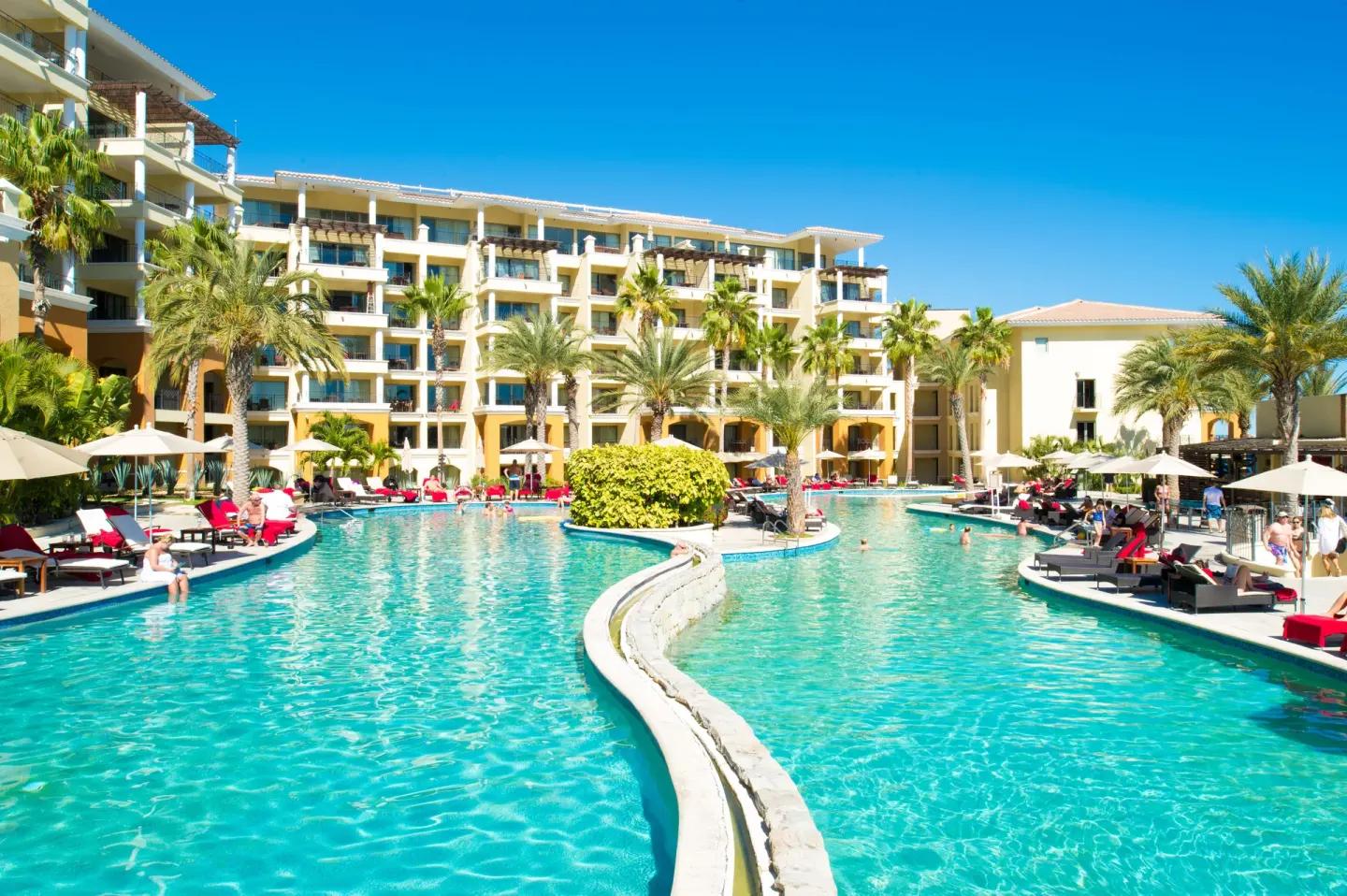 Curving main pool with palms and guestroom balconies at Casa Dorada Los Cabos Resort & Spa.