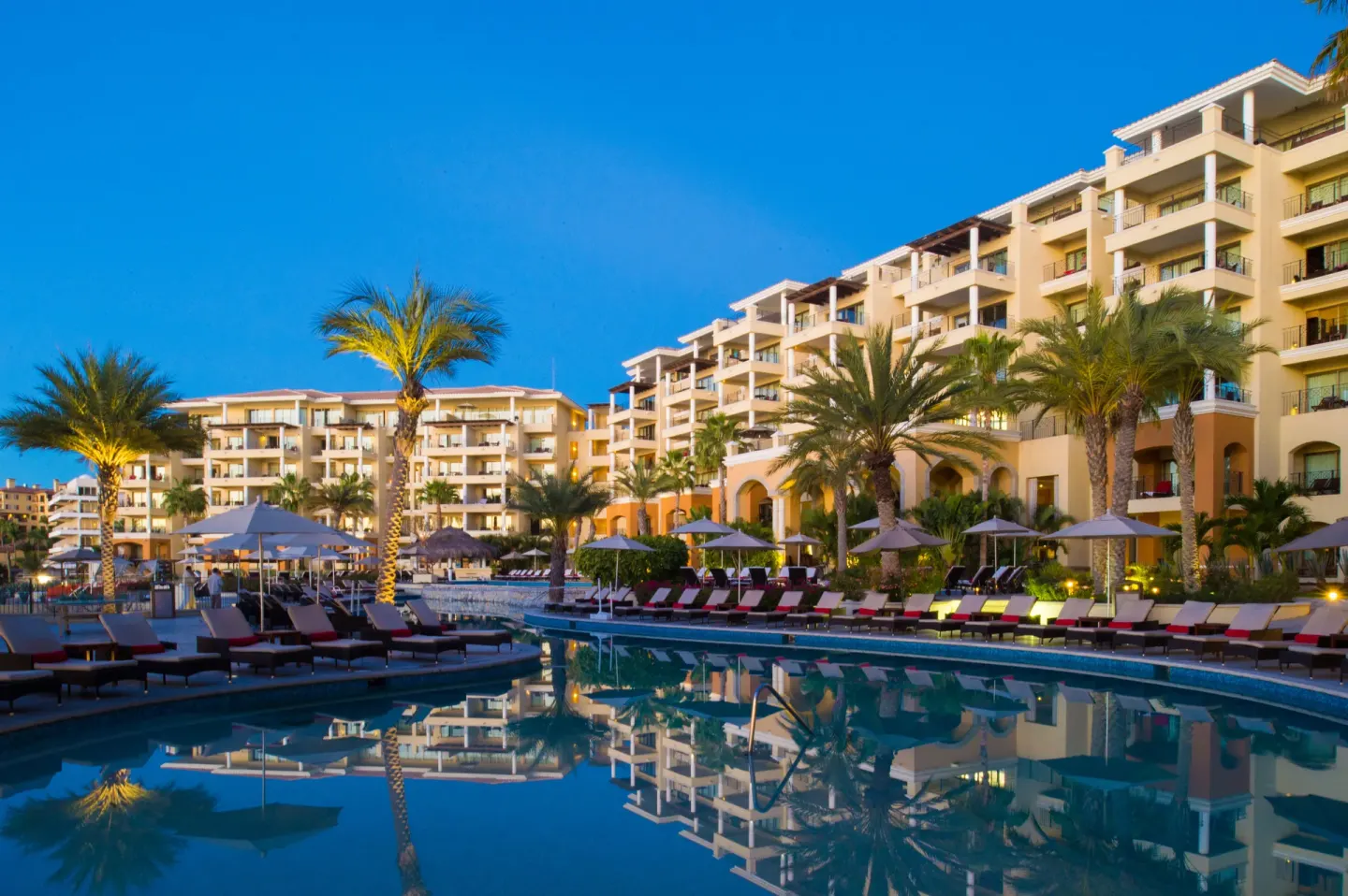 Evening pool scene with illuminated palms and balconies at Casa Dorada Los Cabos Resort & Spa.