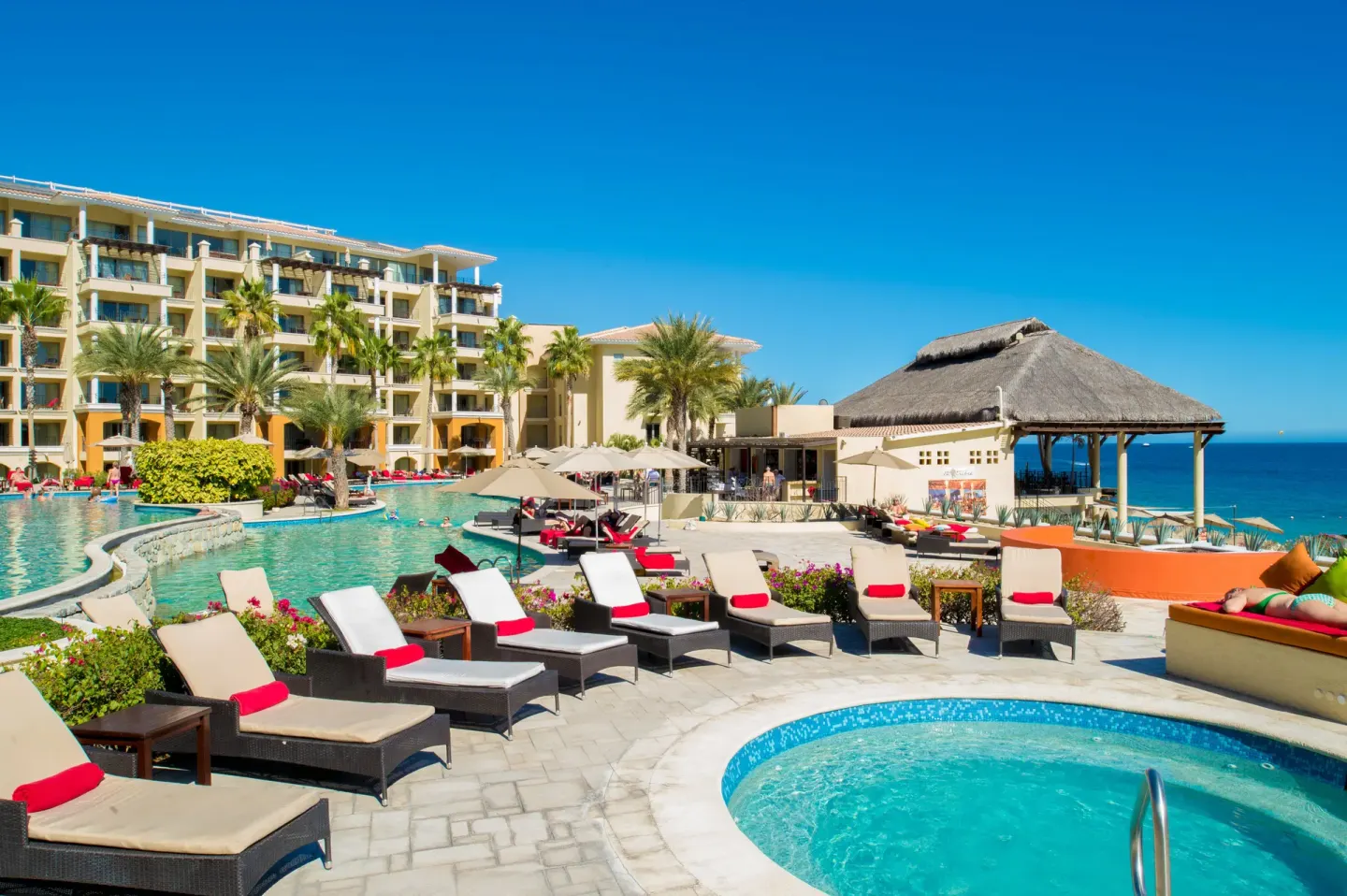 Pool deck with loungers, hot tub, and ocean beyond at Casa Dorada Los Cabos Resort & Spa.