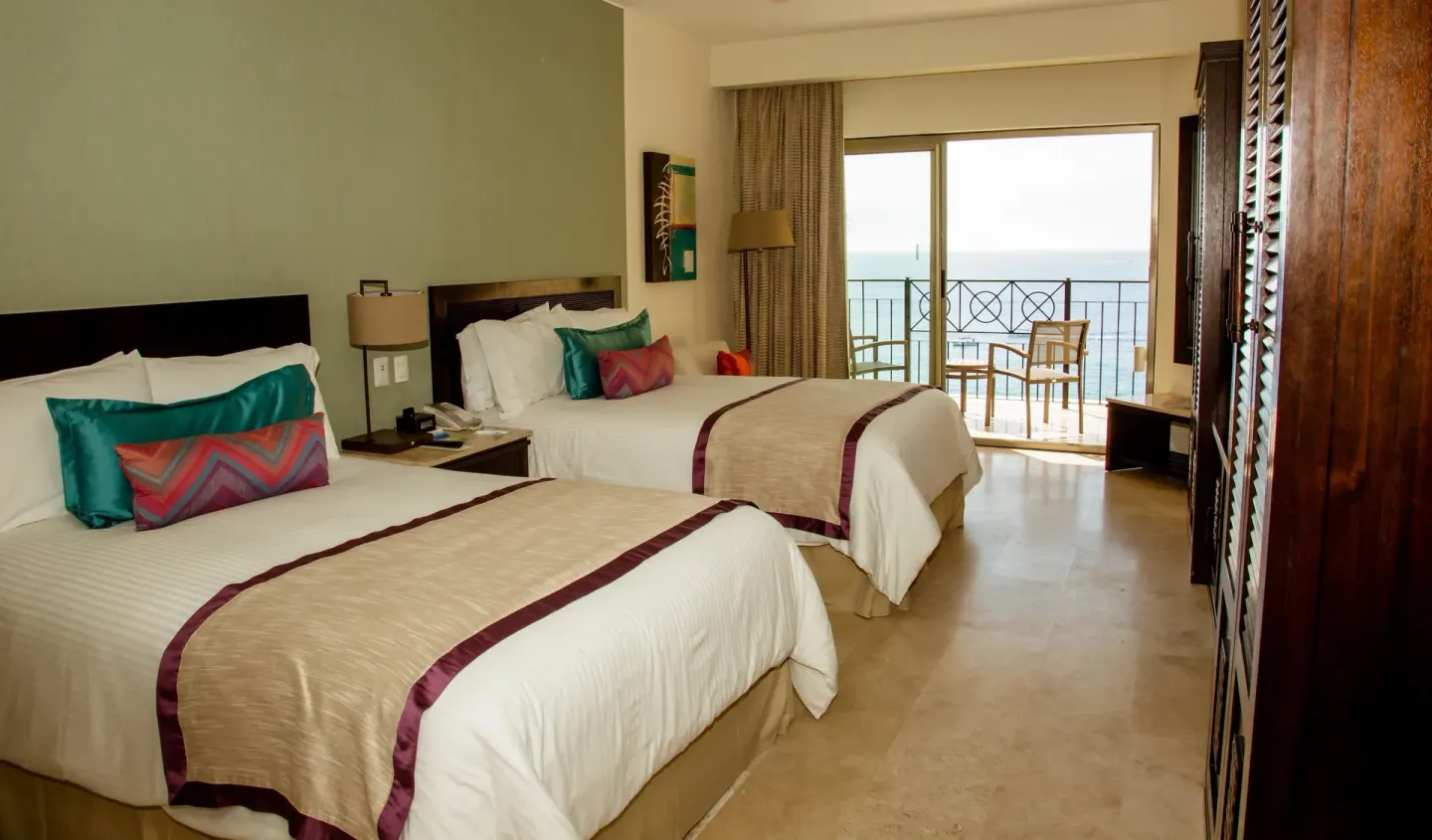 Two double beds and ocean-view balcony in a suite at Casa Dorada Los Cabos Resort & Spa.