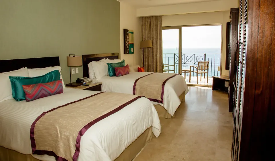 Two double beds and ocean-view balcony in a suite at Casa Dorada Los Cabos Resort & Spa.