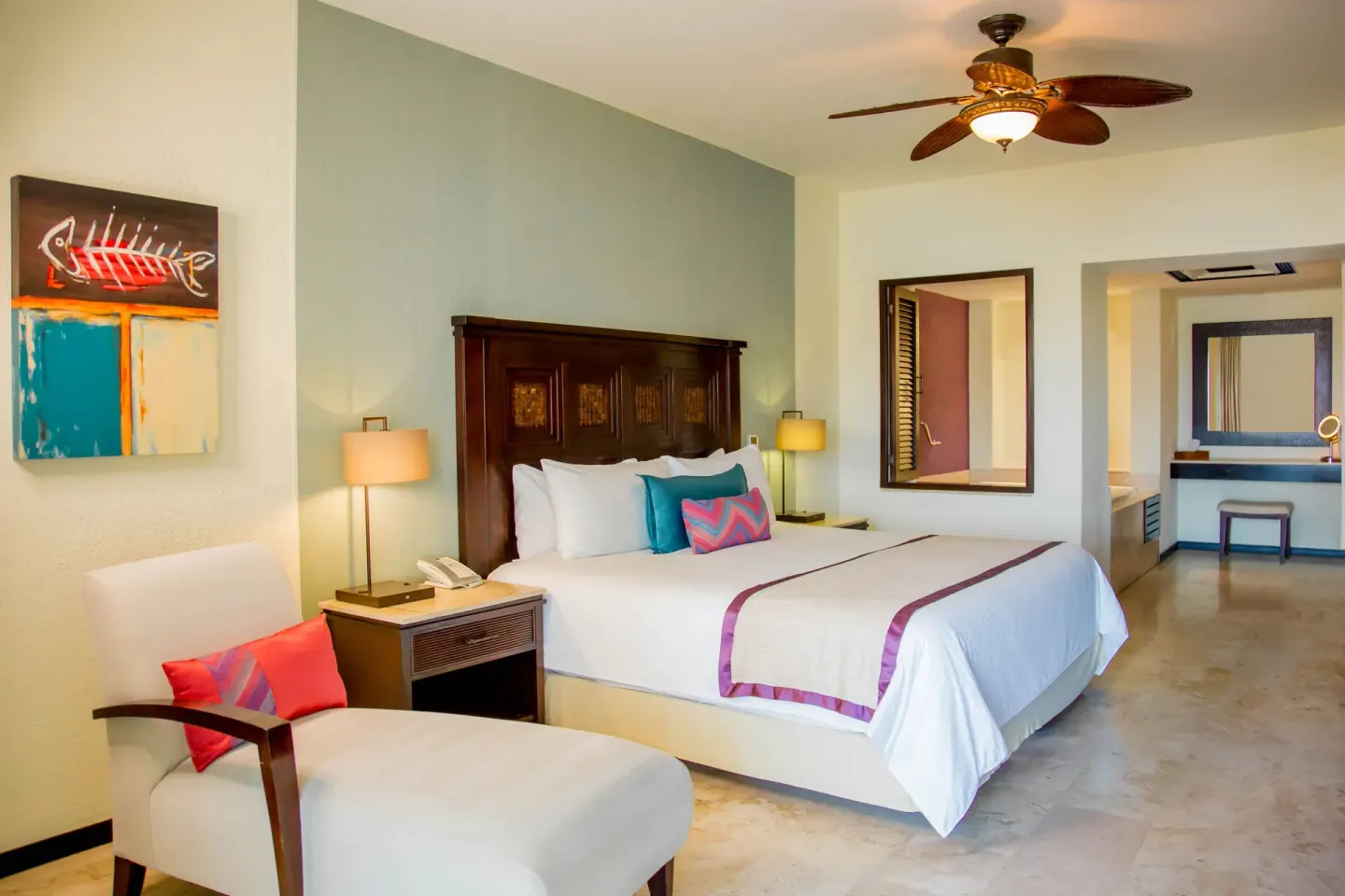 Executive suite king bed with lounge chair and artwork at Casa Dorada Los Cabos Resort & Spa.