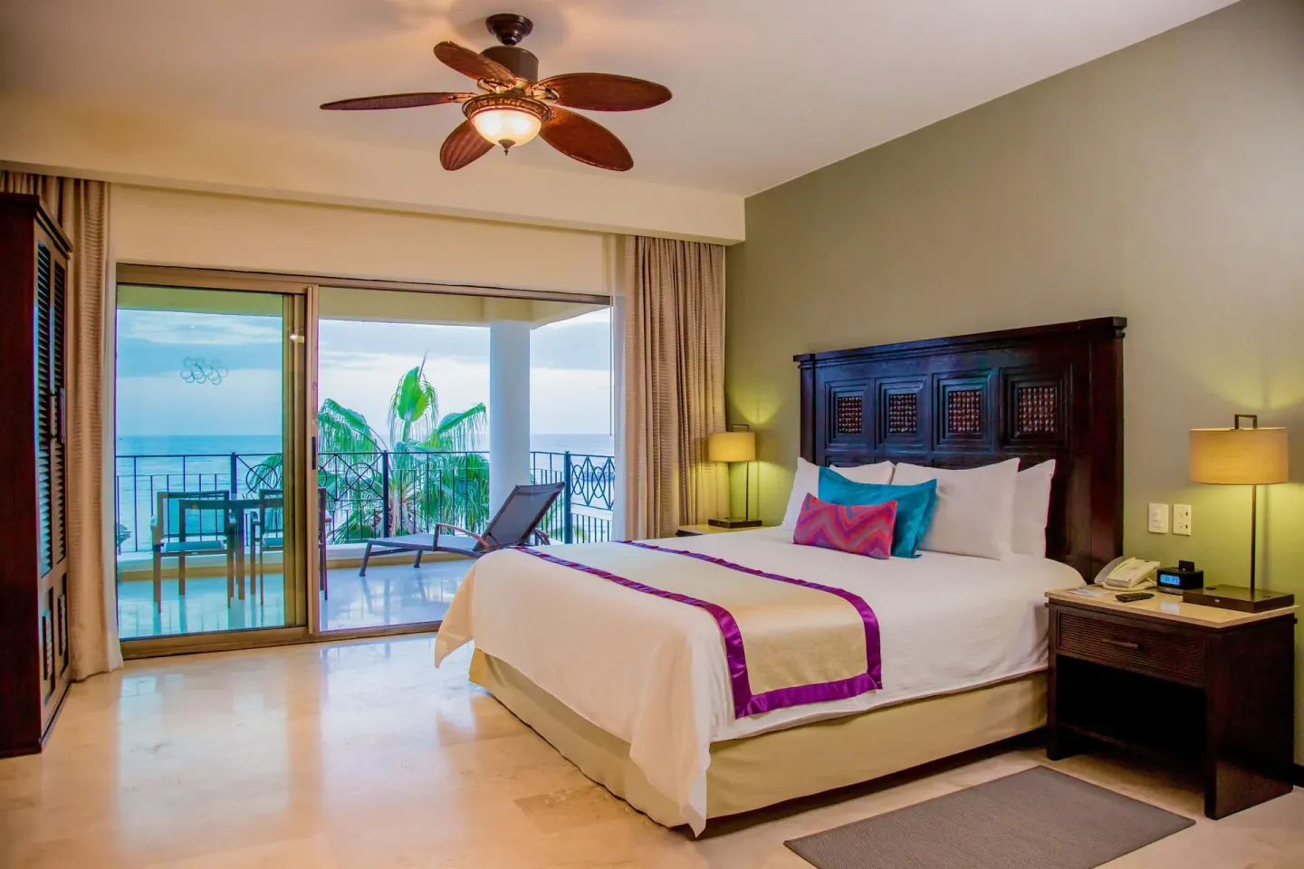 Junior suite king bed beside sliding balcony doors at Casa Dorada Los Cabos Resort & Spa.
