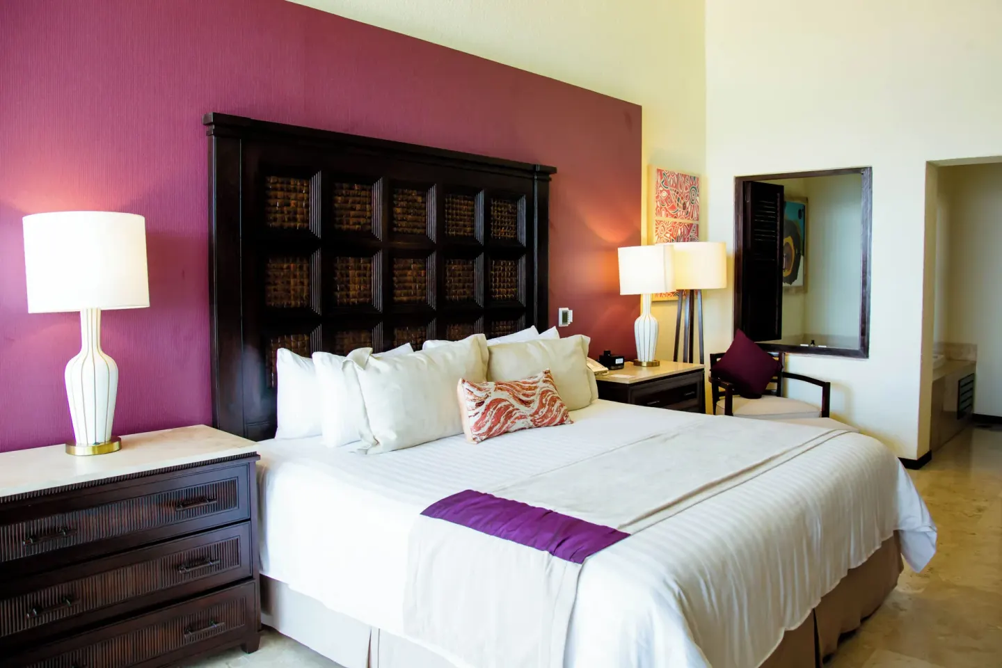 Penthouse bedroom with a king bed and magenta accent wall at Casa Dorada Los Cabos Resort & Spa.