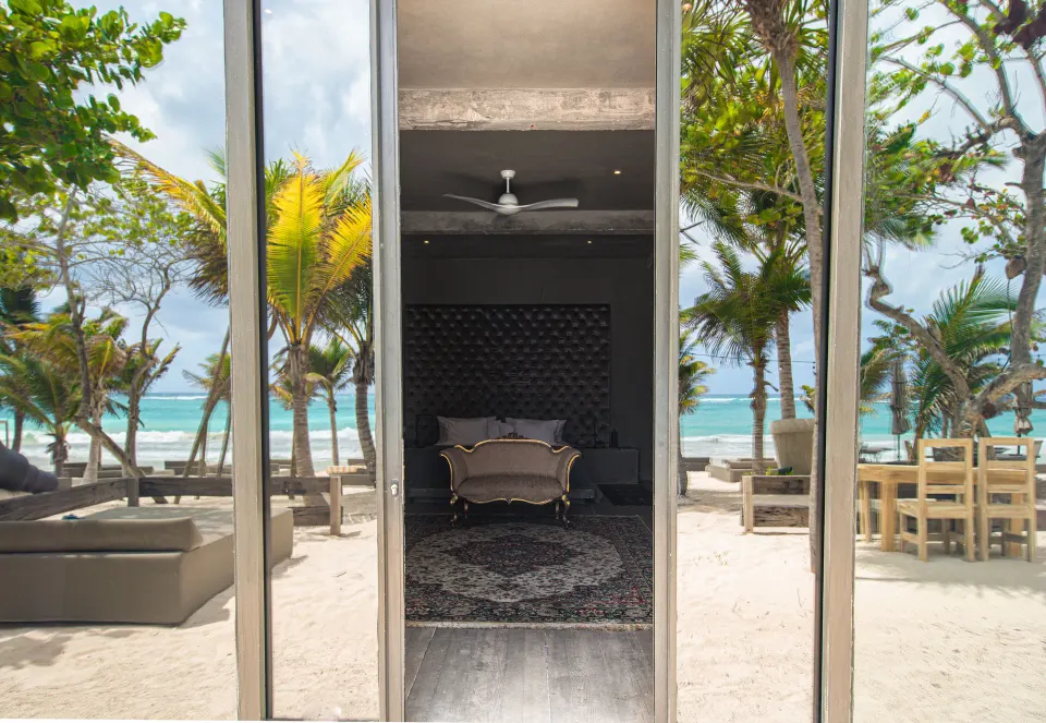 Beachfront suite with sliding glass doors opening to palm-lined sand at Casa Malca