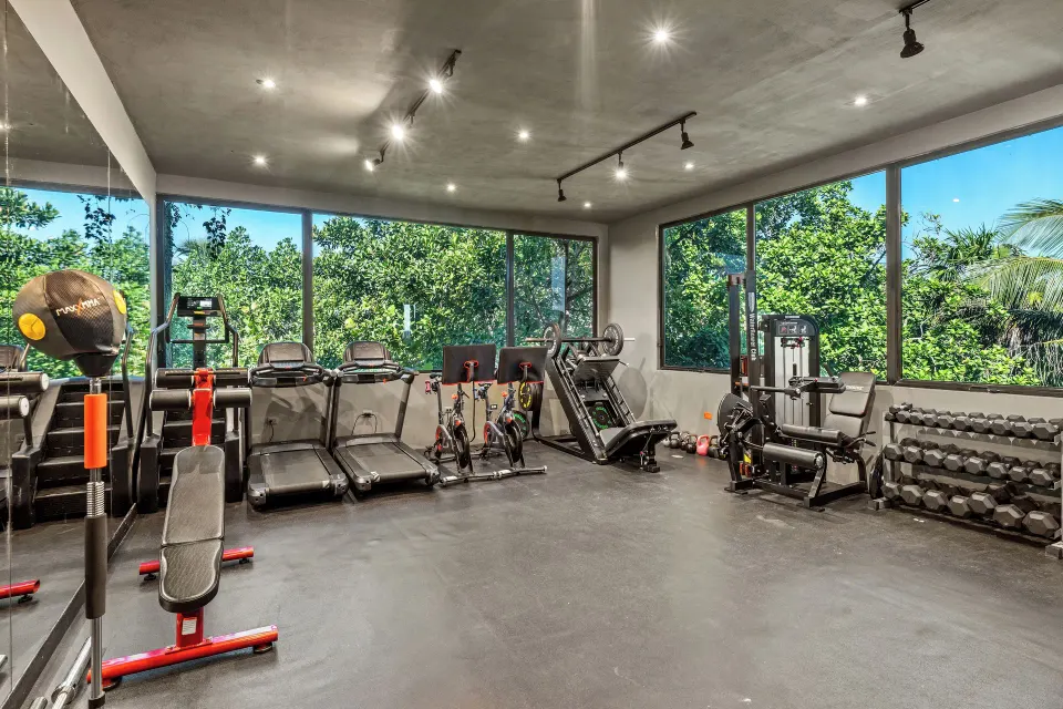 Bright cardio and weights room at Casa Malca with large windows and treadmills.