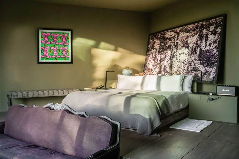 King bed with bench seating and artwork in a guest room at Casa Malca