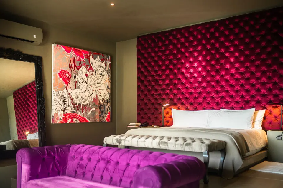 King bed with purple sofa and oversized mirror in a guest room at Casa Malca