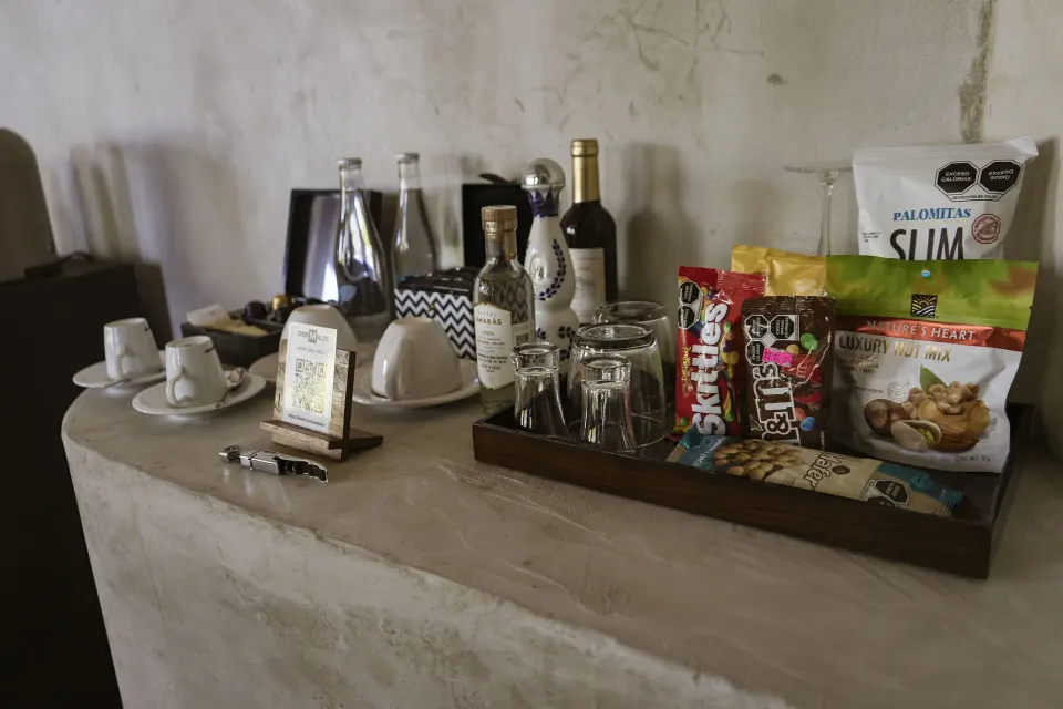 In-room refreshment tray with snacks, bottled water and glassware at Casa Malca