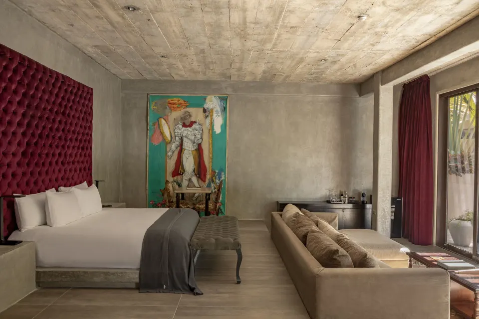Light suite with king bed, red headboard, and colorful artwork at Casa Malca.