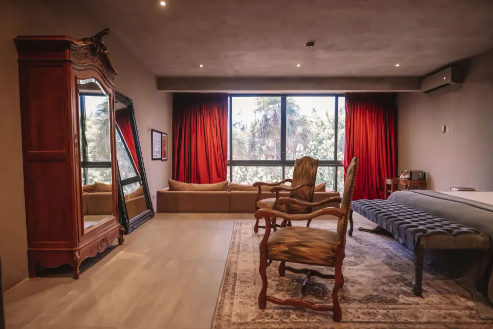 Spacious suite with king bed, sofa, antique chairs and floor-to-ceiling window at Casa Malca