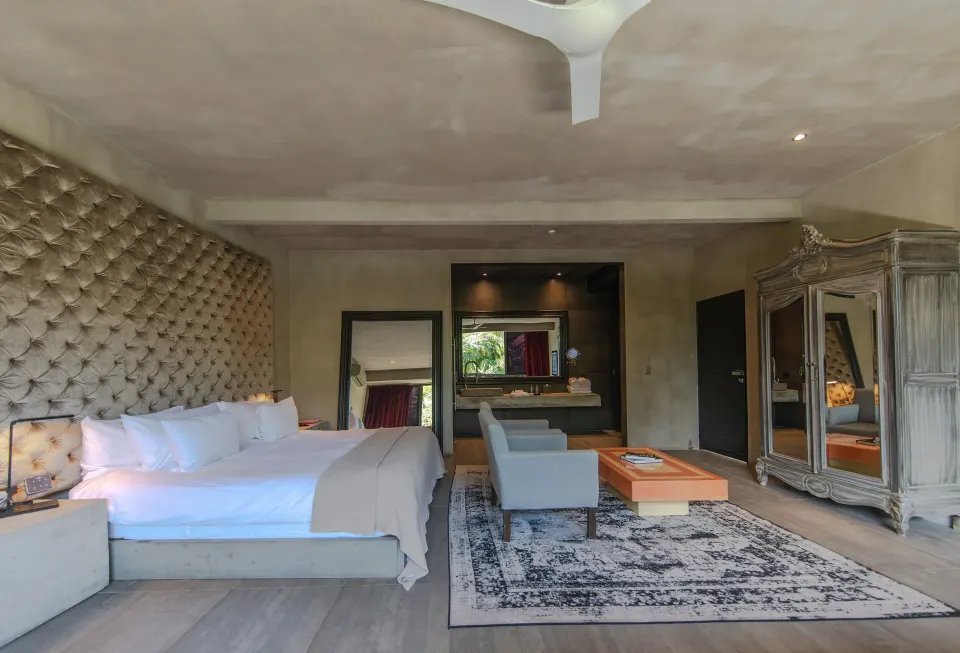 Large suite interior with seating area, bed and tall headboard at Casa Malca