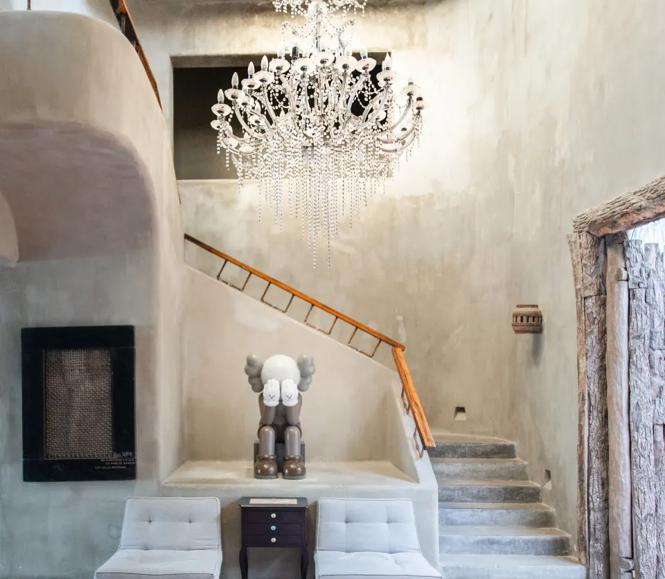 Staircase niche with modern sculpture and chandelier in Casa Malca lobby.