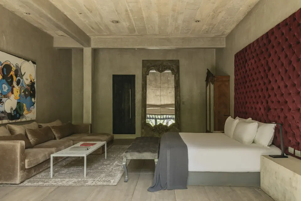Spacious suite with king bed, seating area and red headboard at Casa Malca