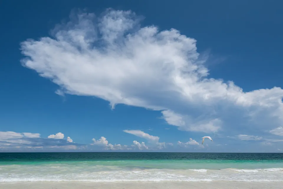 Turquoise ocean and expansive sky from the beach at Casa Malca with a distant parasail