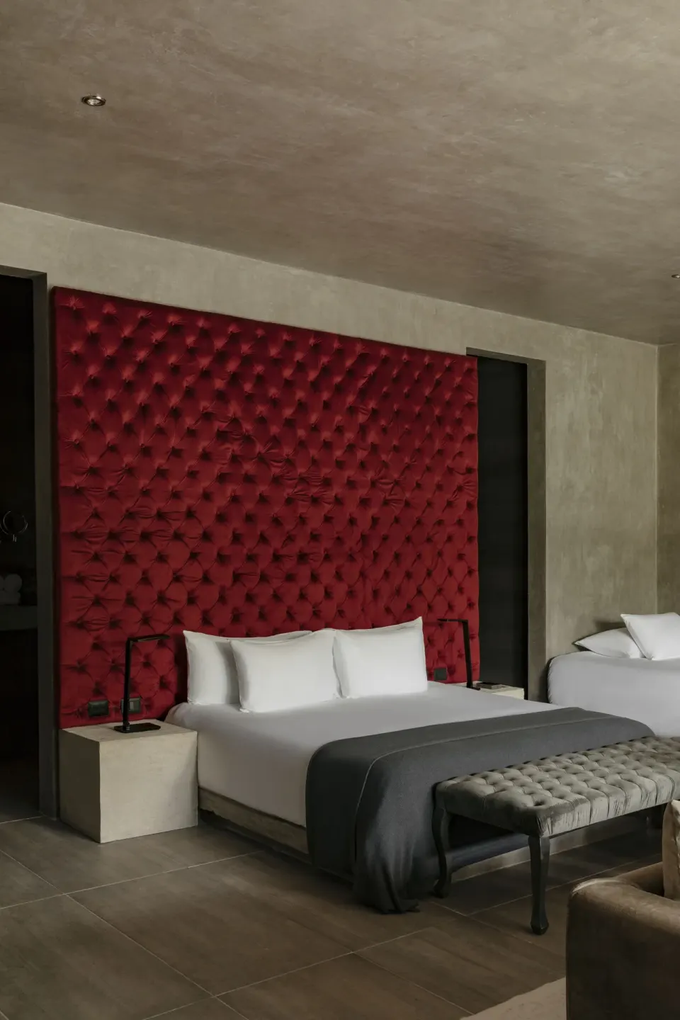 Twin bed setup with tufted red headboard in a guest room at Casa Malca