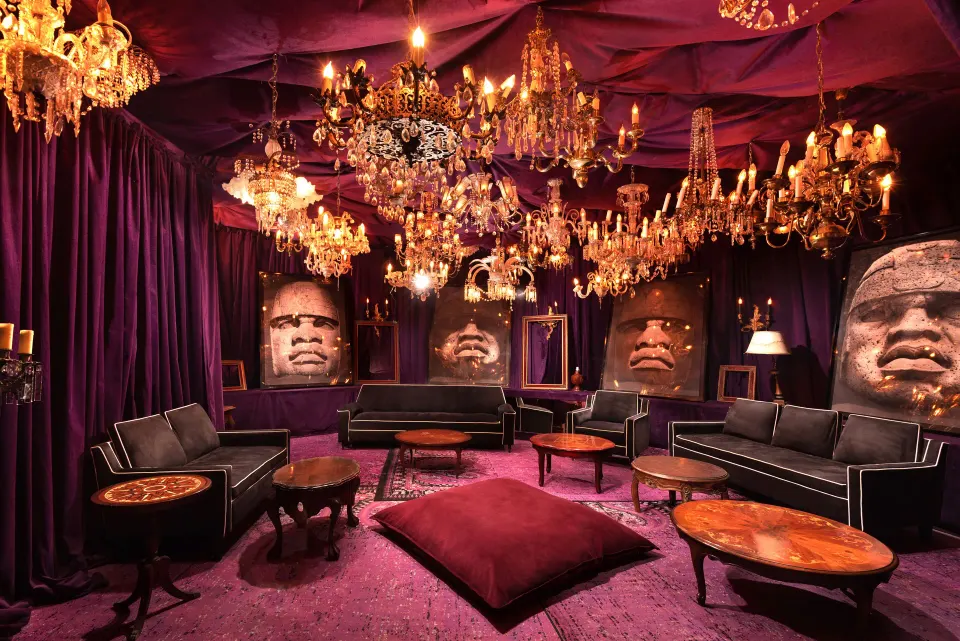 Purple velvet lounge with multiple chandeliers and sculpted faces at Casa Malca