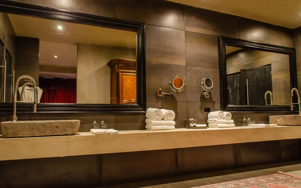 Close-up of the Family Suite bathroom vanity with stacked towels and mirrors at Casa Malca
