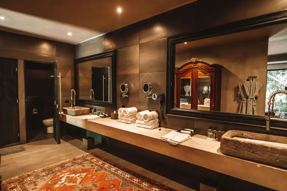 Large bathroom in the Family Suite with long double vanity, stone sinks and decorative rug at Casa Malca