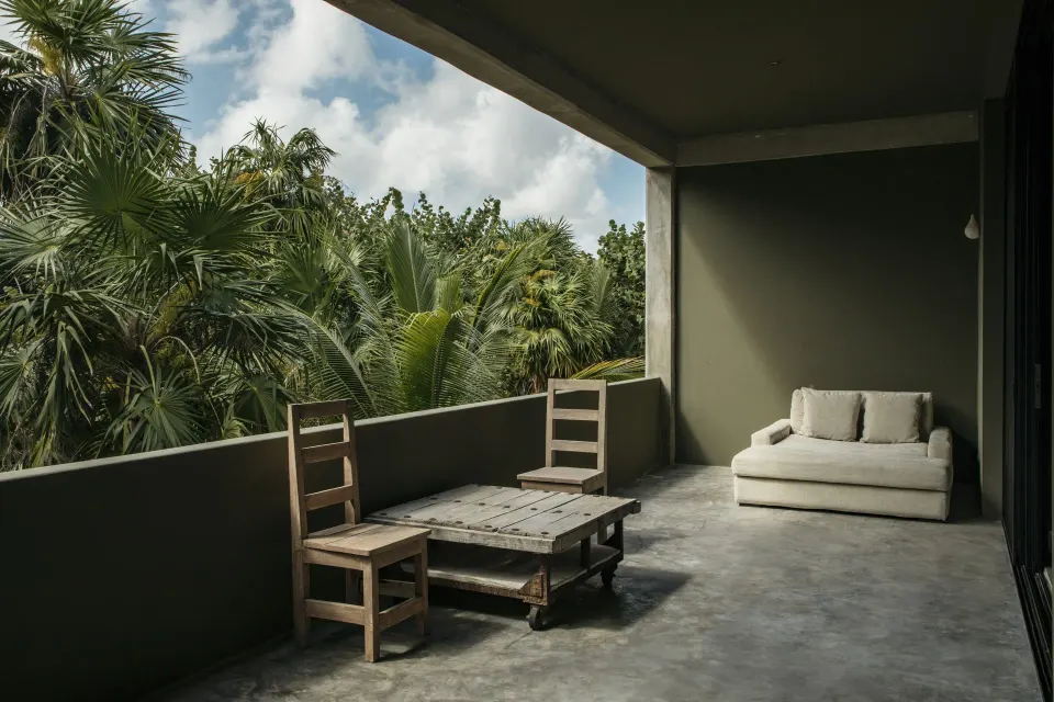 Private terrace of the Family Suite with wooden chairs and a lounge sofa overlooking lush garden at Casa Malca
