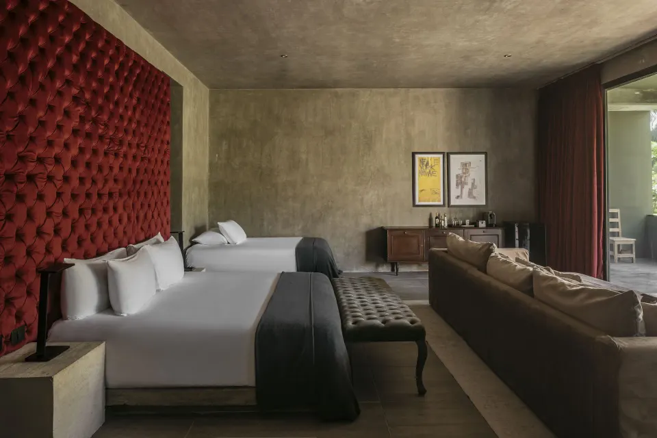 Family Suite interior with two beds, red tufted headboard and sofa at Casa Malca