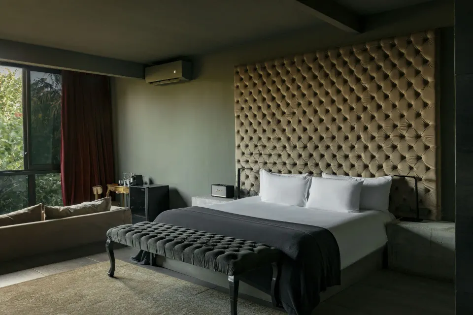Junior Suite beachfront king bed with tufted headboard and sofa by a corner window at Casa Malca