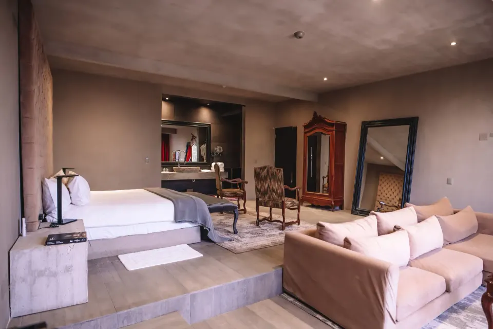 Junior Suite beachfront king bed on raised platform with seating area and mirror at Casa Malca