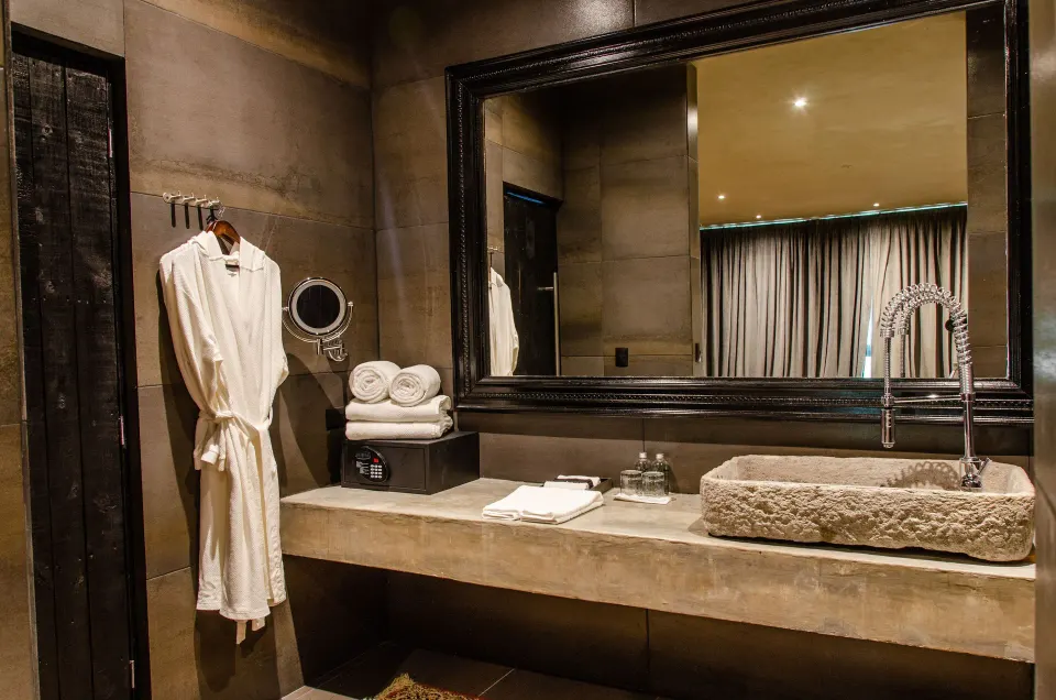 Bathroom sink and mirror with robe and towels in a Junior Suite Garden View at Casa Malca
