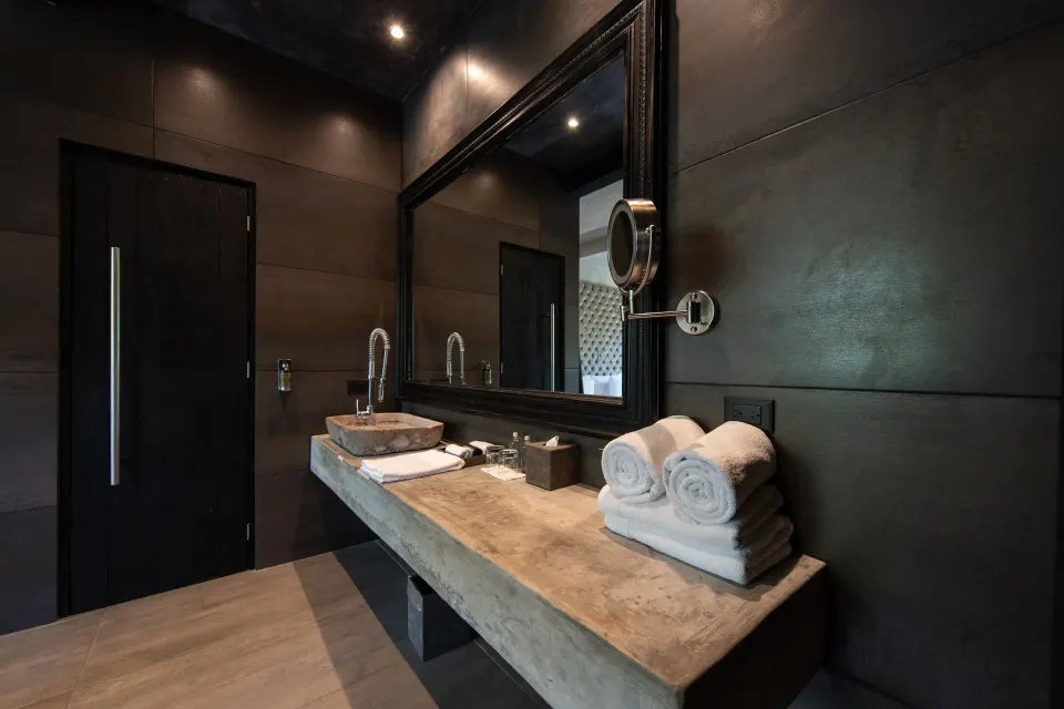 Concrete vanity with stacked towels and magnifying mirror in Junior Suite Garden View at Casa Malca