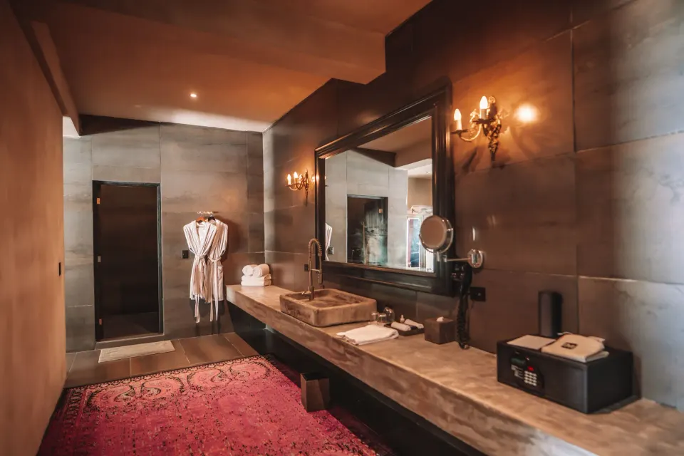 Bathroom vanity with mirror and robes in a Junior Suite Garden View at Casa Malca
