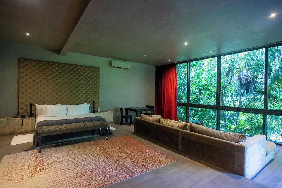 Junior Suite Garden View at Casa Malca showing bed, sofa and floor-to-ceiling windows with jungle outside