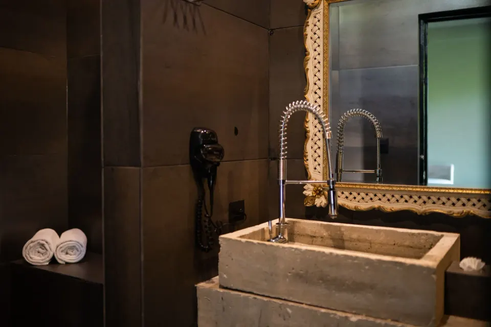 Close-up of stone sink, brass-topped faucet and wall hairdryer at Casa Malca