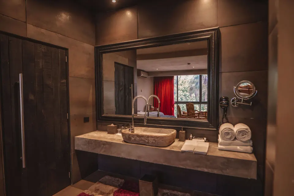 Bathroom vanity with stone sink and large mirror in Casa Malca suite