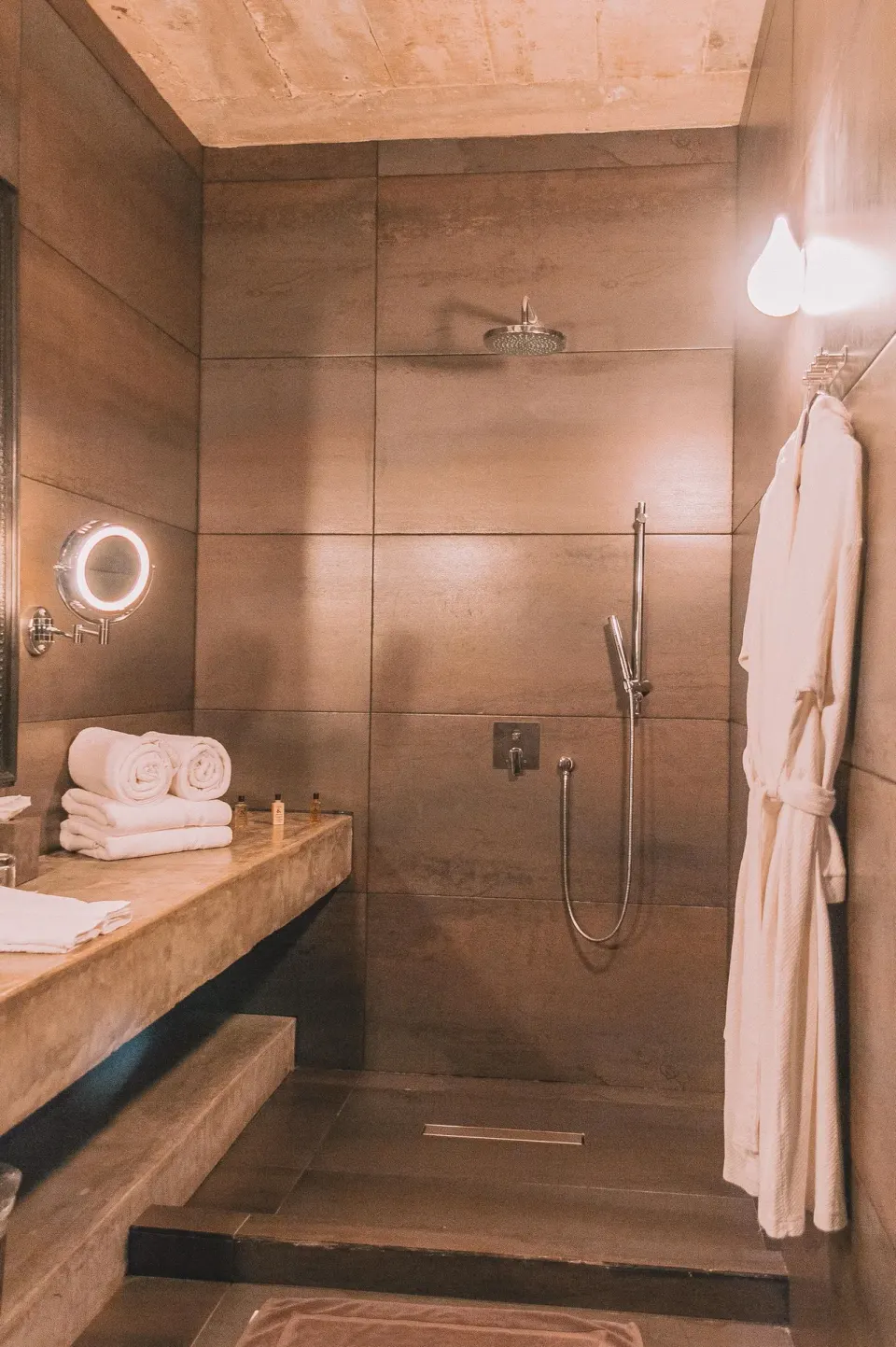 Walk-in shower with rainfall head and robe hanging in Casa Malca bathroom